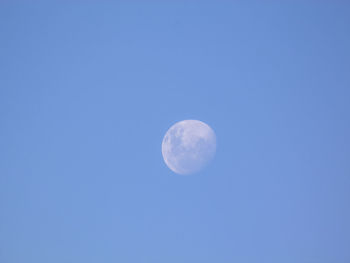 Low angle view of moon against clear blue sky