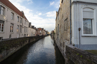Canal amidst buildings in city against sky
