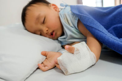 Injured boy sleeping on bed at home