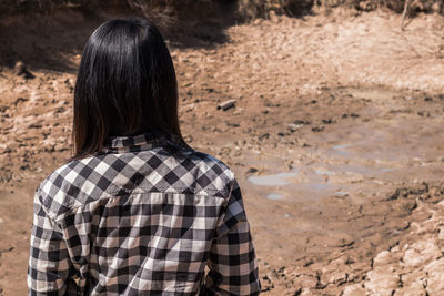 Rear view of woman standing on barren land