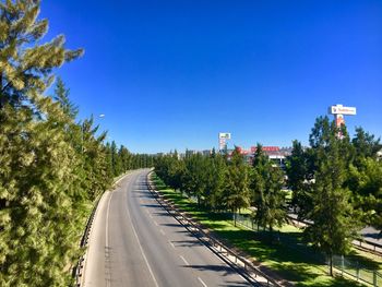 Road amidst trees against clear blue sky