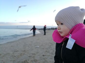 Close-up of cute girl standing at beach during winter