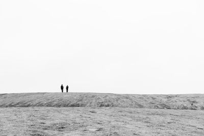 People standing on land against clear sky