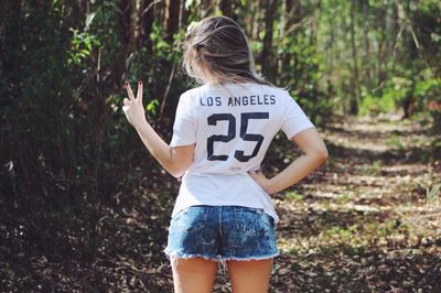 Full length of girl standing on tree trunk in forest