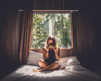 Young woman sitting on bed at home