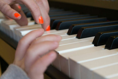 Cropped hands of child and mother playing piano
