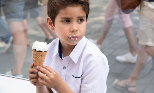 Cute child boy with a dirty face eats ice cream, the child enjoys dessert