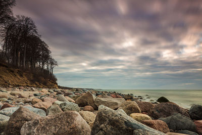 Rocks by sea against sky during sunset