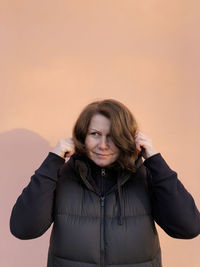 Portrait of woman standing against gray background