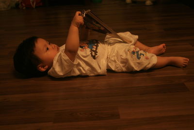 Baby playing with hand fan while lying on floor