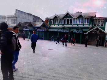 People walking on street amidst buildings in city