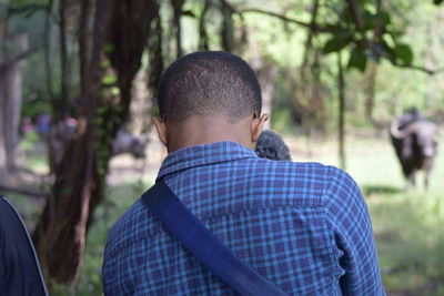 Rear view of teenage boy with buffalo in background