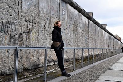 Woman standing on footbridge against sky