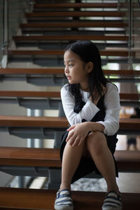 Girl looking away while sitting on steps