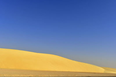 Scenic view of desert against clear blue sky