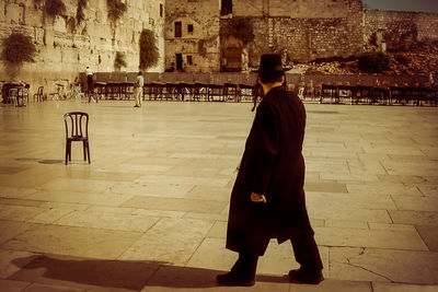 Rear view of man standing on cross in city