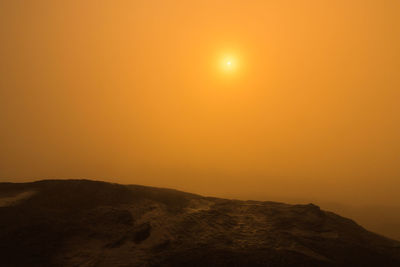 Scenic view of mountains against orange sky