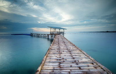 Pier over sea against sky during sunset