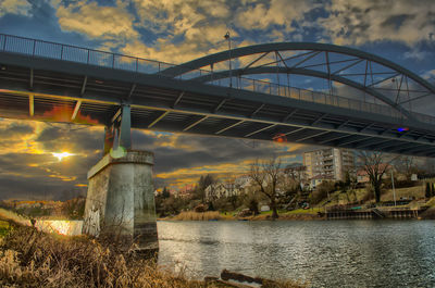 Bridge over river against cloudy sky
