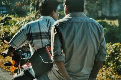 Rear view of man with friend riding motorcycle