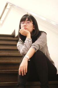 Beautiful young woman sitting against wall