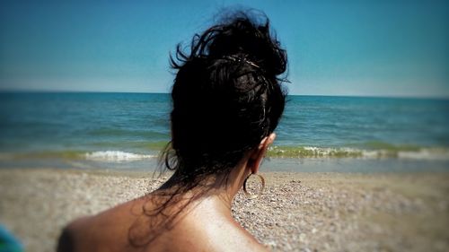 Rear view of woman on beach against sky