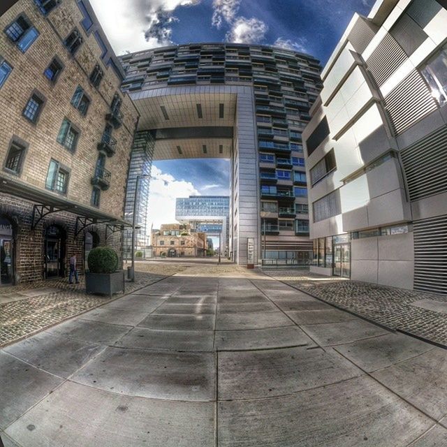 architecture, building exterior, built structure, sky, the way forward, city, diminishing perspective, cloud - sky, street, building, transportation, road, cloud, vanishing point, day, empty, sunlight, outdoors, road marking, window