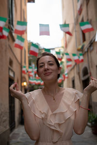 Portrait of woman smiling while standing against italian flags amidst buildings in city