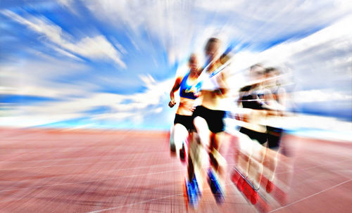 Blurred motion of people running against cloudy sky