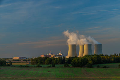 Smoke emitting from factory against sky