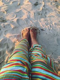 Low section of woman standing on sand at beach