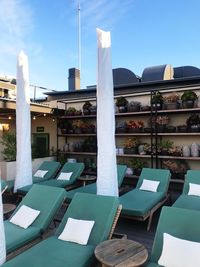 Chairs and table by swimming pool against buildings