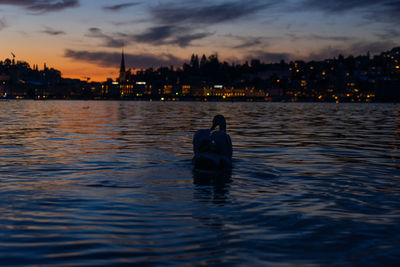 Man in sea against sky during sunset