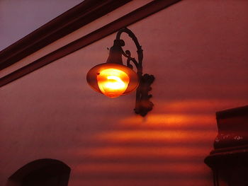 Close-up of illuminated lamp against orange sky