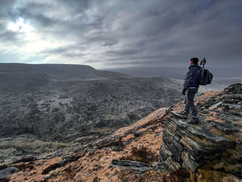 Man standing on rock against sky