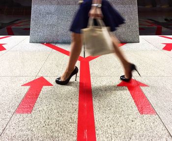 Low section of woman walking on road in city