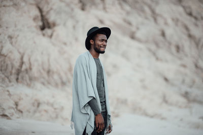 Side view of young man wearing hat standing outdoors