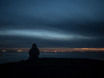 Rear view of silhouette man looking at sea against sunset sky