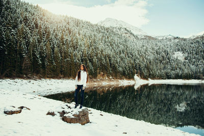 Person standing by lake against sky during winter