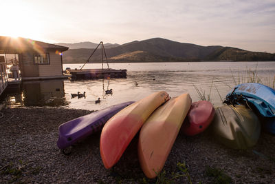 Boats at lakeshore against sky during sunset