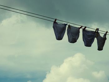 Low angle view of panties drying on clothesline against cloudy sky