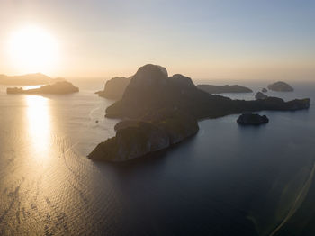 Rocks in sea against sky during sunset