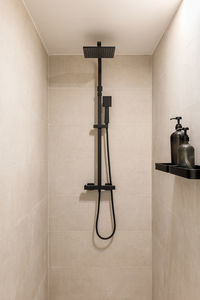 Black shower and ceramic tiled wall. vertical view of modern minimalist interior of beige color