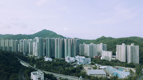 Modern buildings by mountains against sky in city