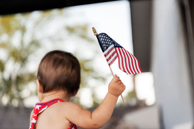 Rear view of baby girl holding flag