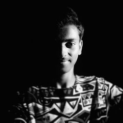 Close-up portrait of young man over black background