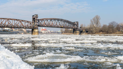 Bridge over river against sky during winter