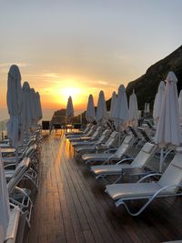 Panoramic view of lounge chairs and tables at beach during sunset