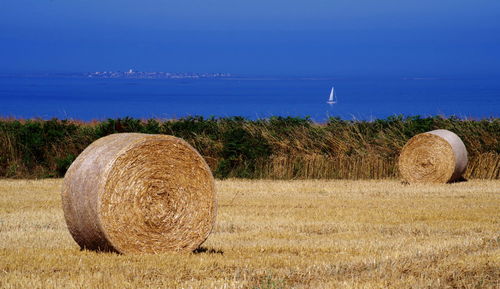 Hay bales on field against sky