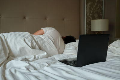 Midsection of man using laptop on bed at home